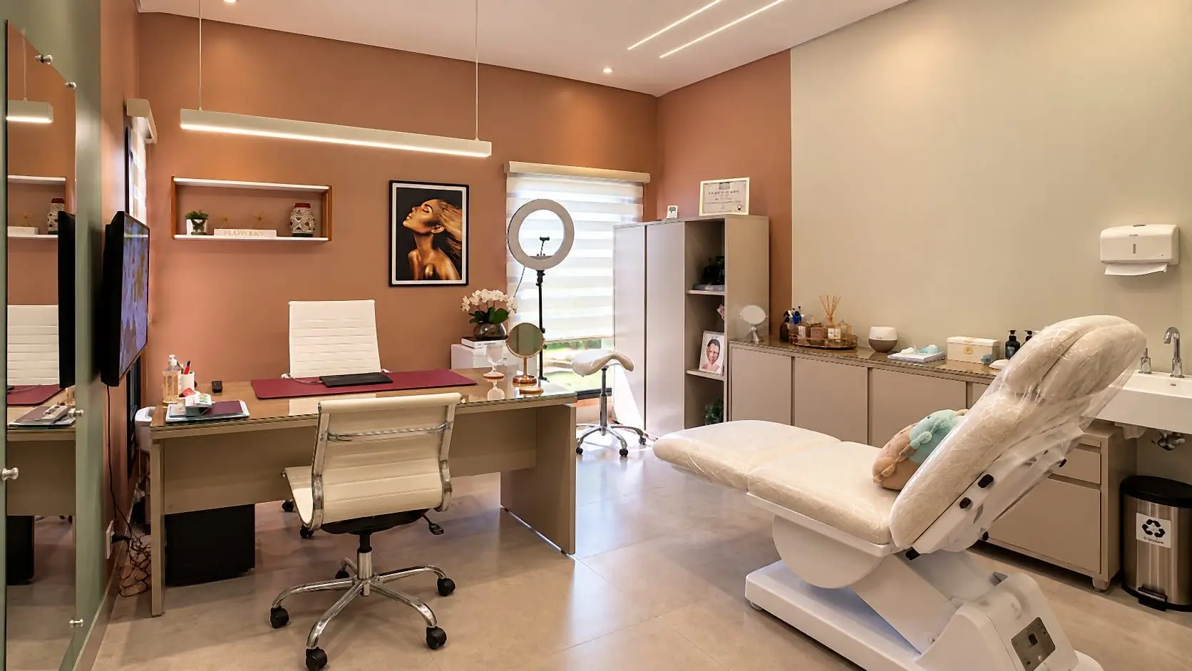 Flowers Clinic treatment room, with a treatment bed, desk and ring light