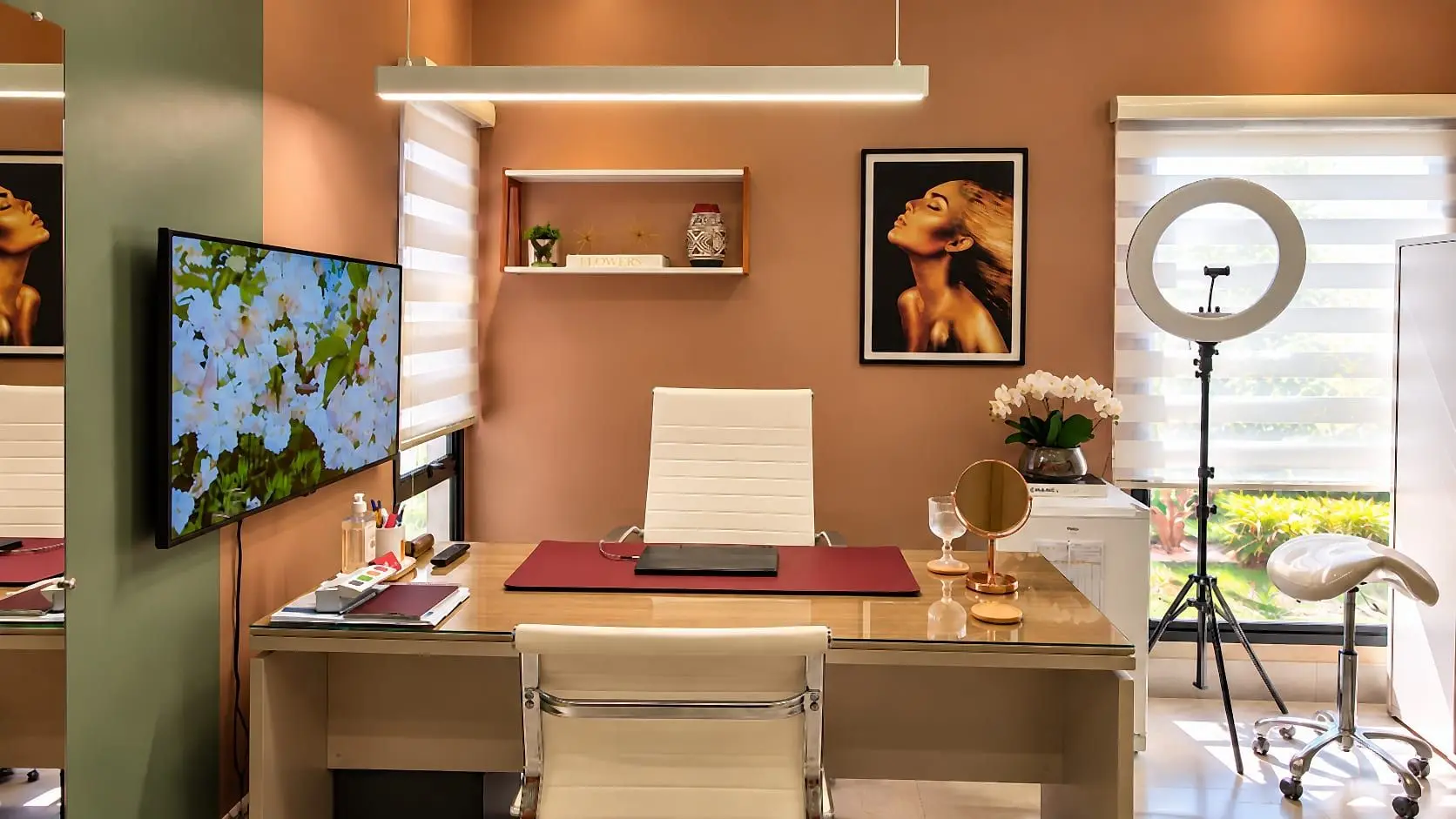 Flowers Clinic treatment room, with a desk, framed art on the wall and a ring light